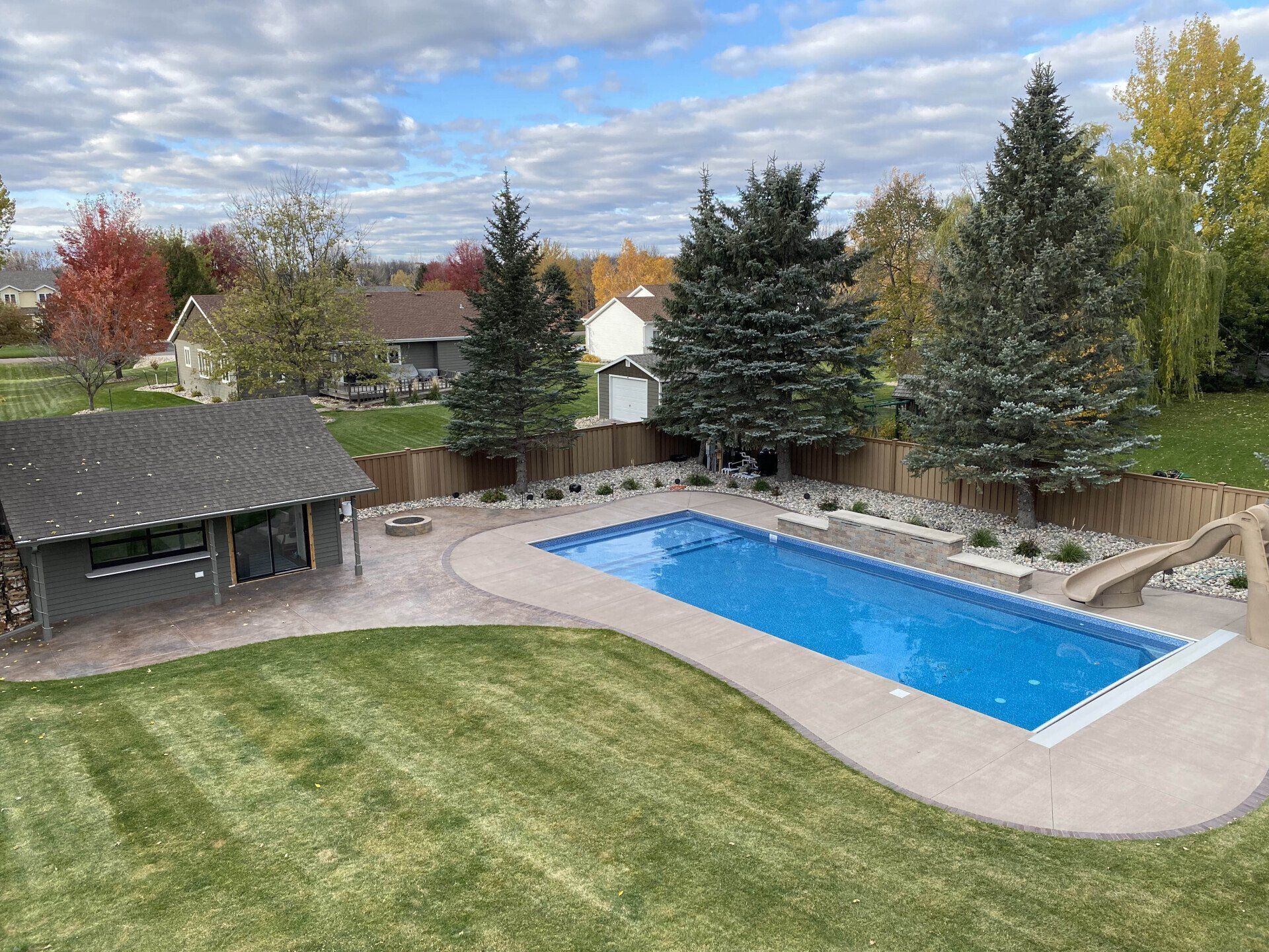 An aerial view of a large swimming pool in a backyard surrounded by trees.