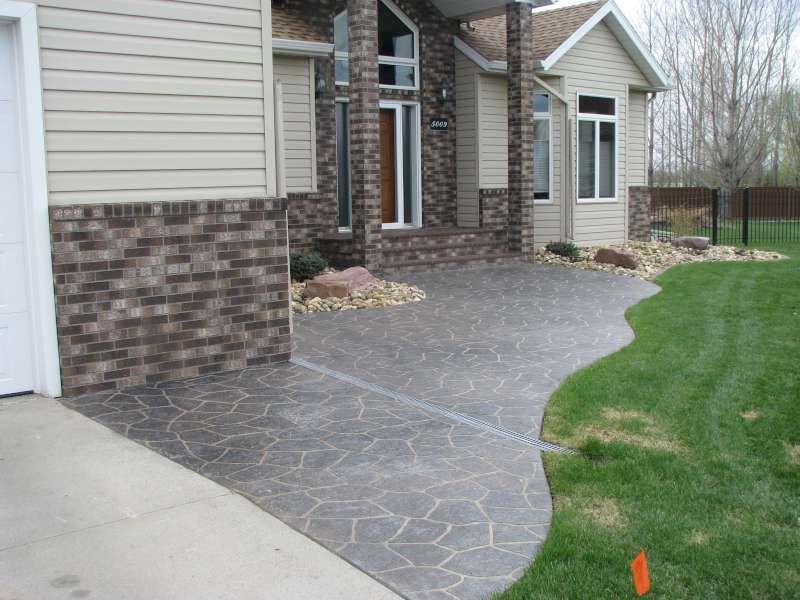 A brick house with a concrete walkway in front of it