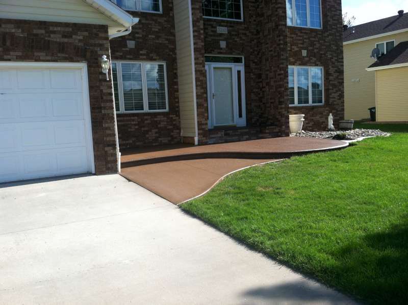 A brick house with a white garage door and a concrete driveway in front of it.