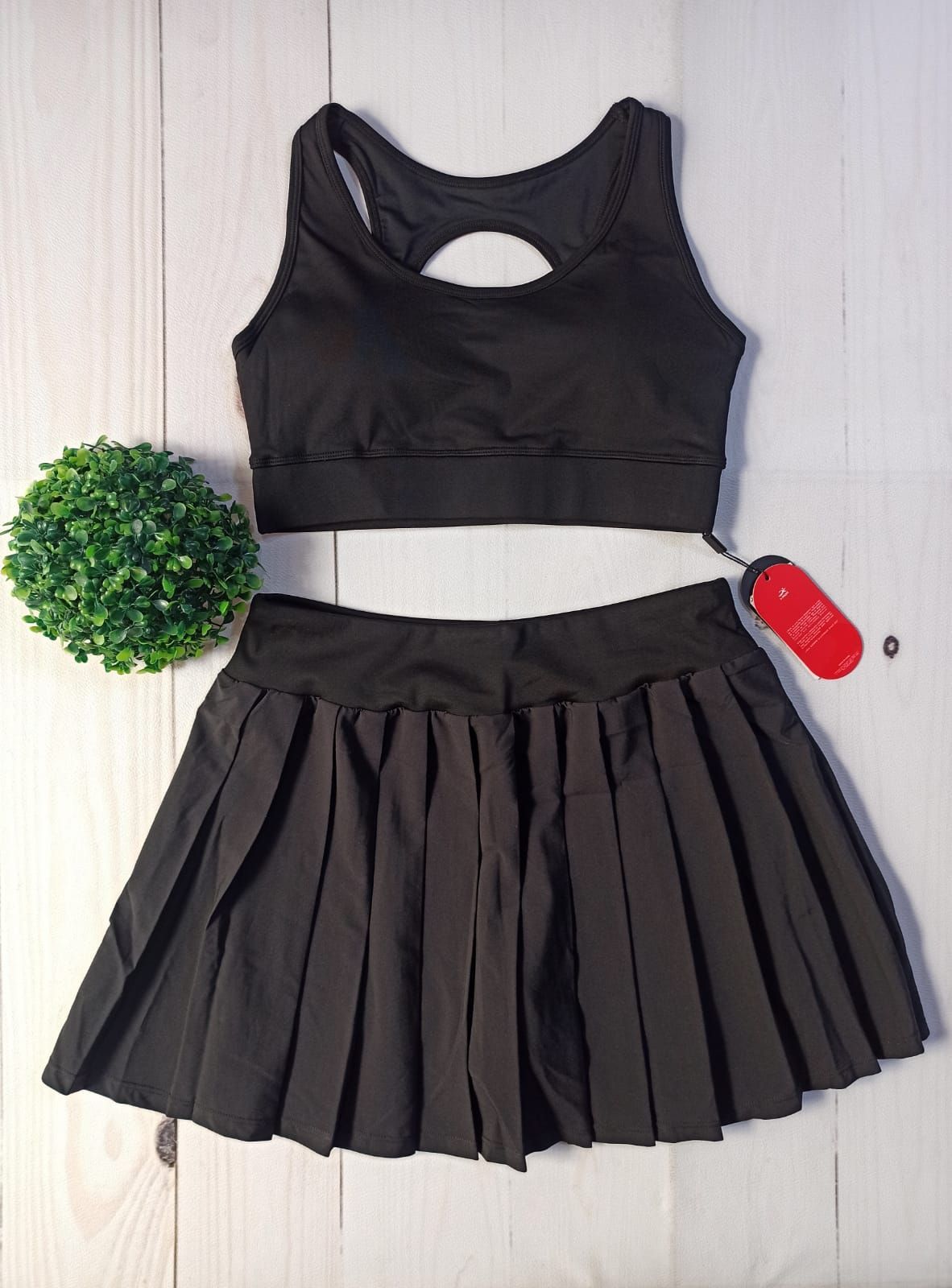 Conjunto deportivo en tonos pastel con tops cortos y faldas plisadas dispuestas sobre un suelo de madera clara.