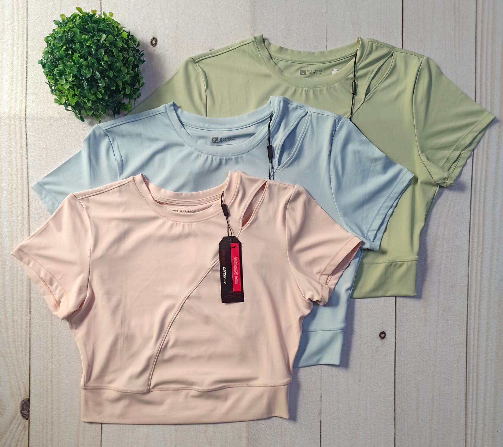Tres camisetas de colores pastel dobladas, en tonos melocotón