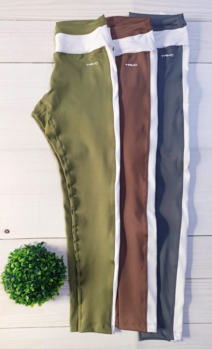 Una modelo luce unos leggings de color verde oliva con rayas blancas en los laterales, combinados con zapatillas blancas.