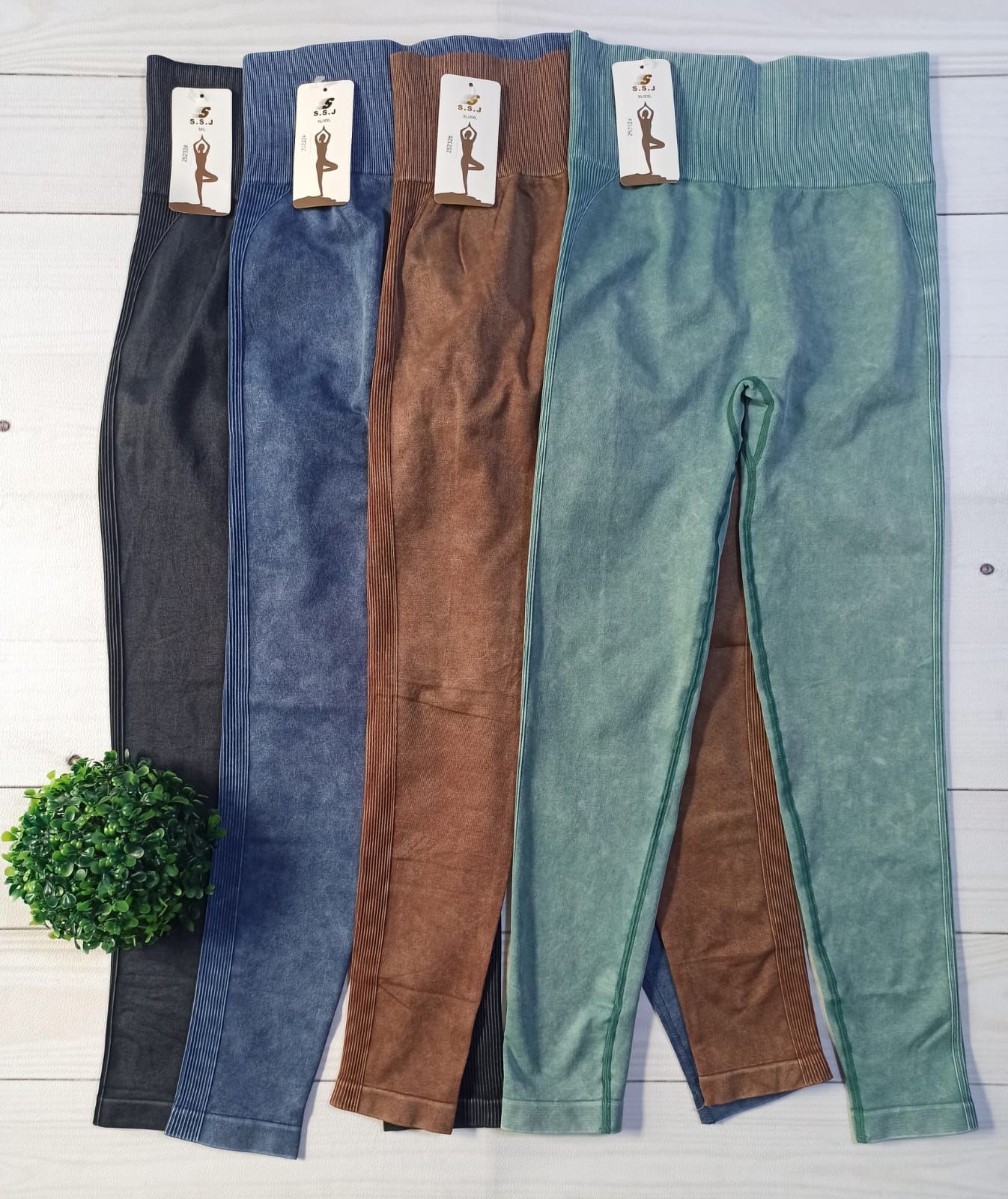 Cuatro pares de pantalones deportivos ajustados en gris, azul, marrón y menta, extendidos sobre un fondo blanco.
