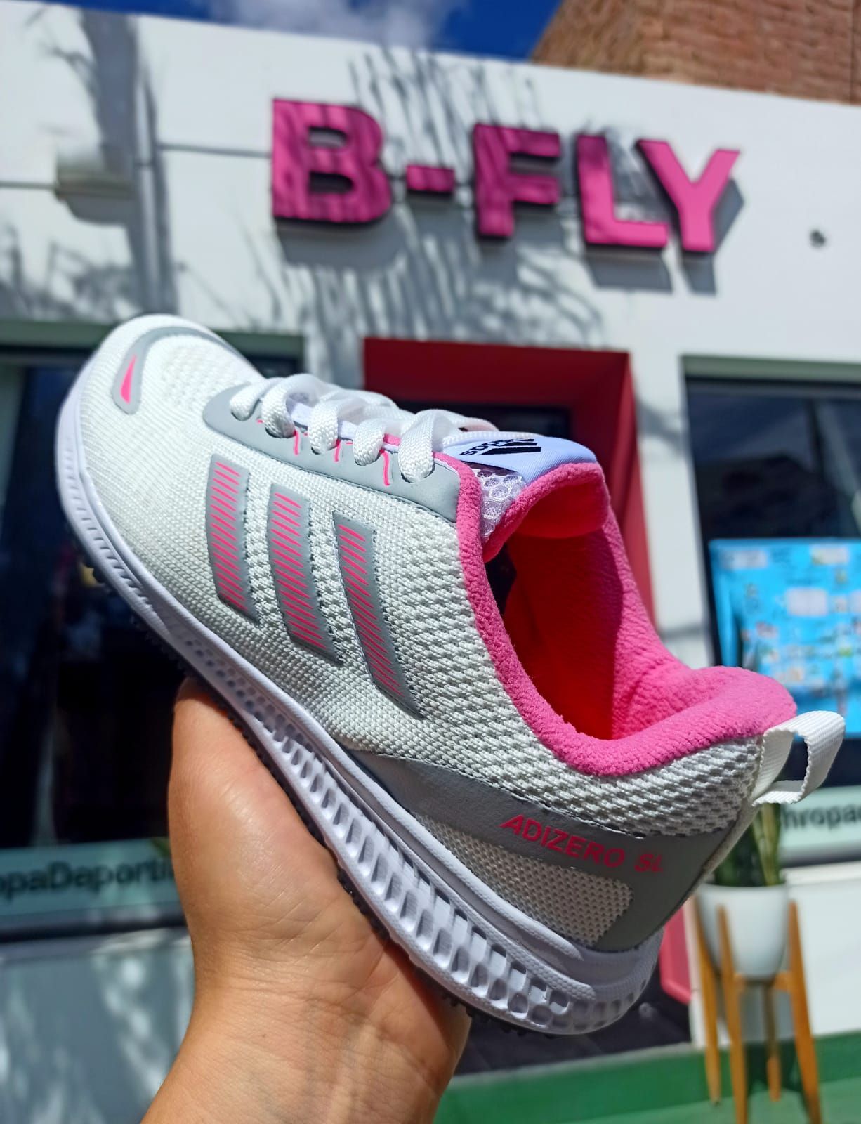 Zapatillas deportivas plateadas y rosas expuestas en el exterior de una tienda B-FLY.