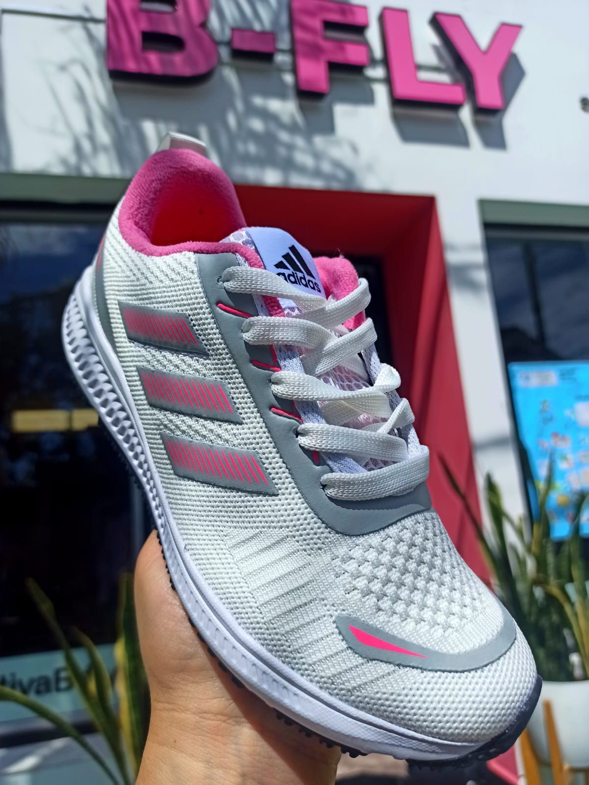Zapatillas deportivas plateadas y rosas expuestas en el exterior de una tienda B-FLY.