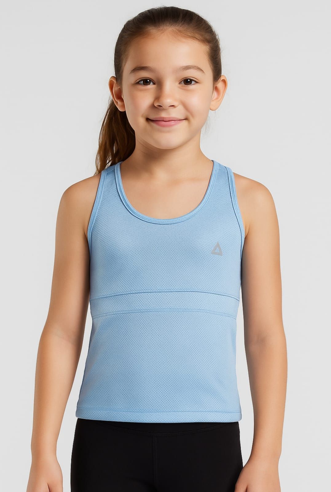 Niño sonriente con una camiseta sin mangas azul claro y pantalones negros sobre un fondo gris.