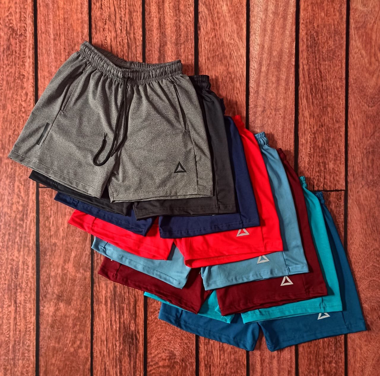 Pila de pantalones cortos deportivos de colores sobre una superficie de madera.