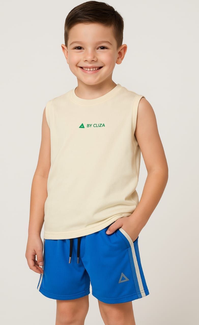 Niña sonriente modelando una camiseta sin mangas color crema y pantalones cortos azules sobre un fondo liso.