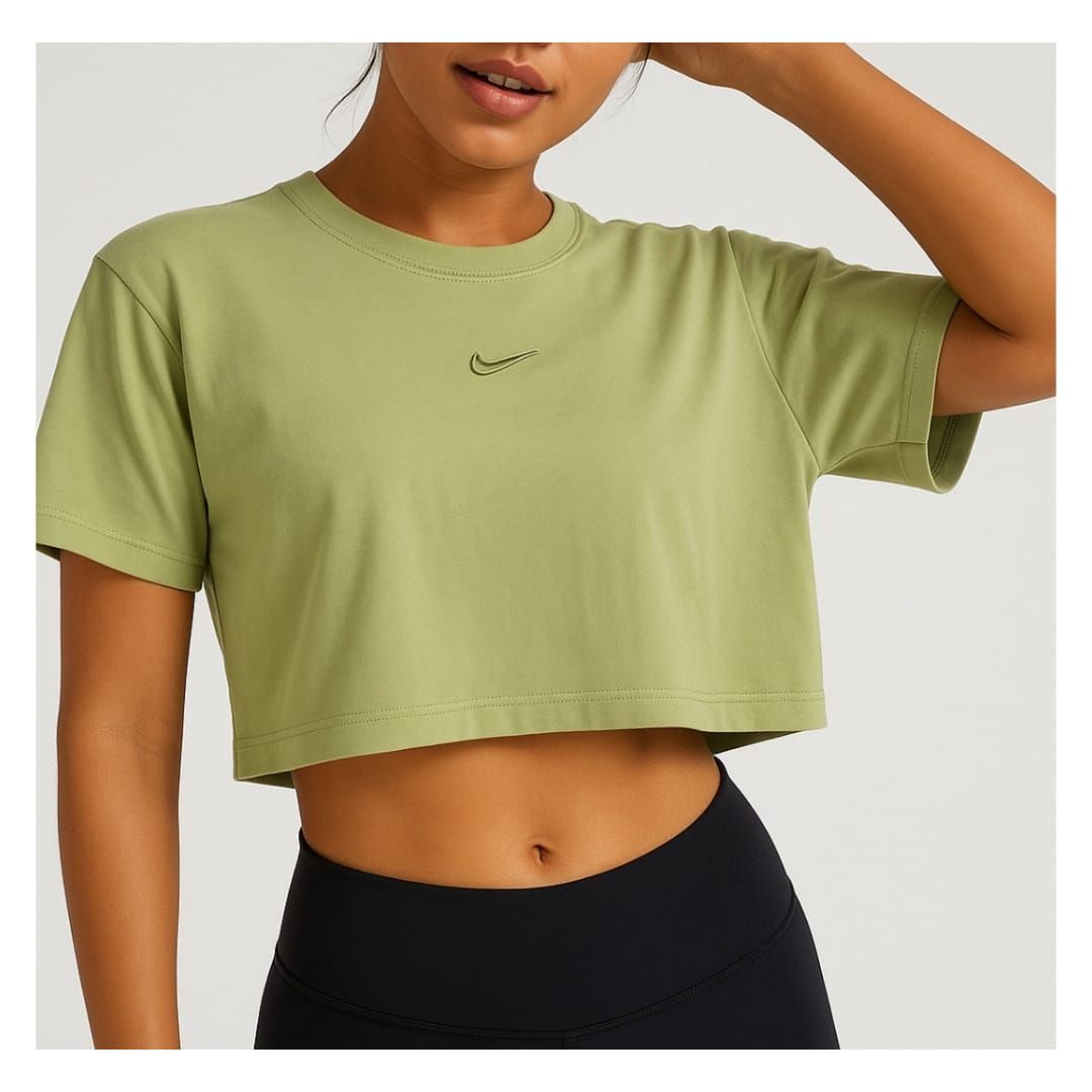 Mujer con camiseta corta verde oliva y leggings negros, posando sobre un fondo claro.