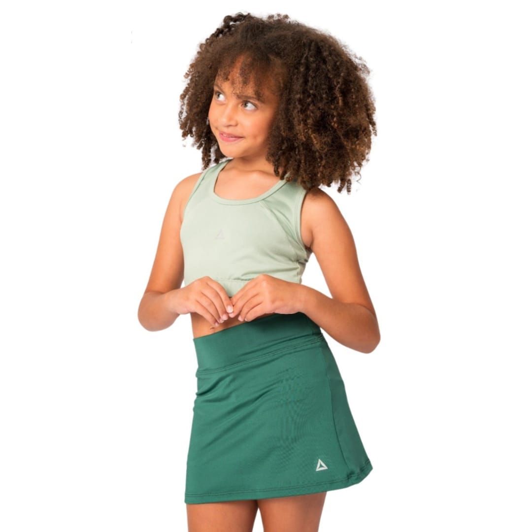 Mujer posando con un top corto color menta y una falda verde sobre un fondo blanco.