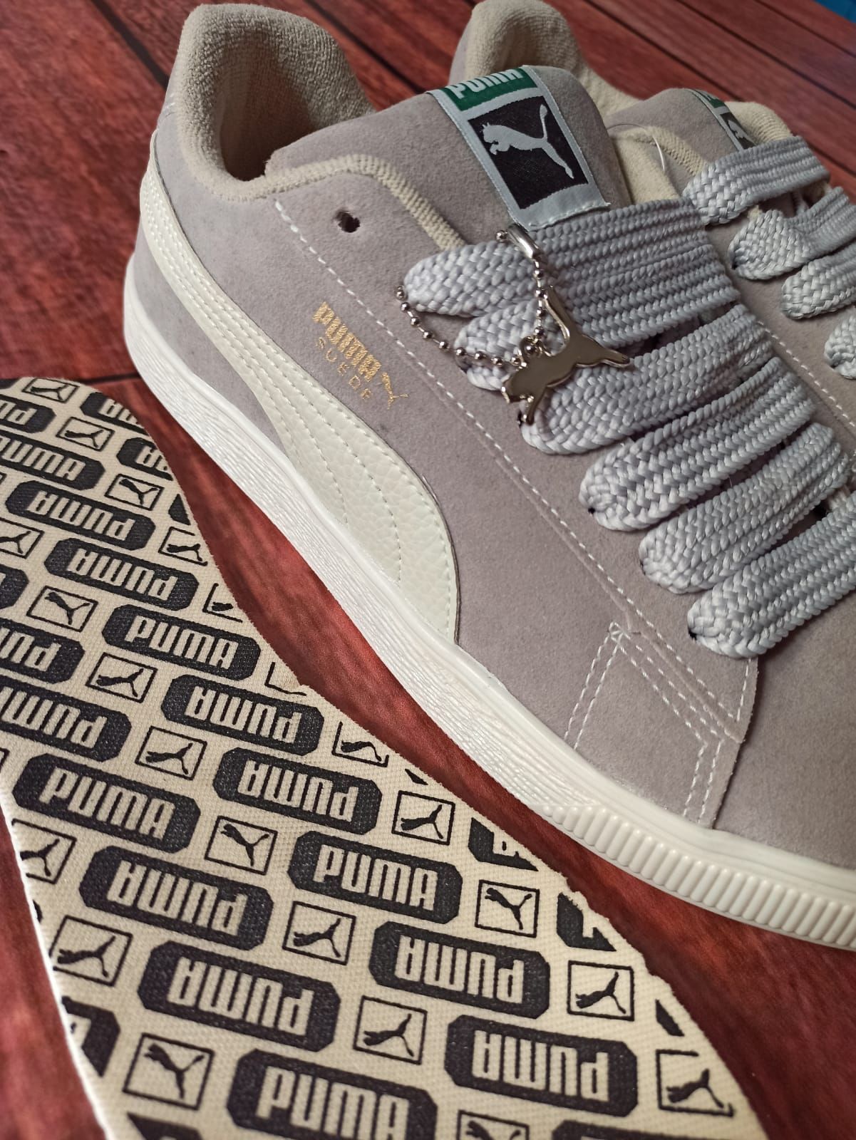 Un par de zapatillas grises con suelas estampadas en blanco y negro sobre un suelo de madera.