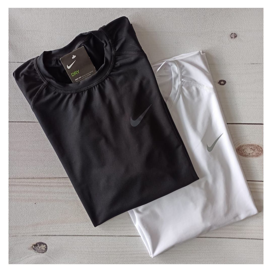 Dos camisetas Under Armour dobladas, una blanca y otra gris, yacían sobre un suelo de baldosas.
