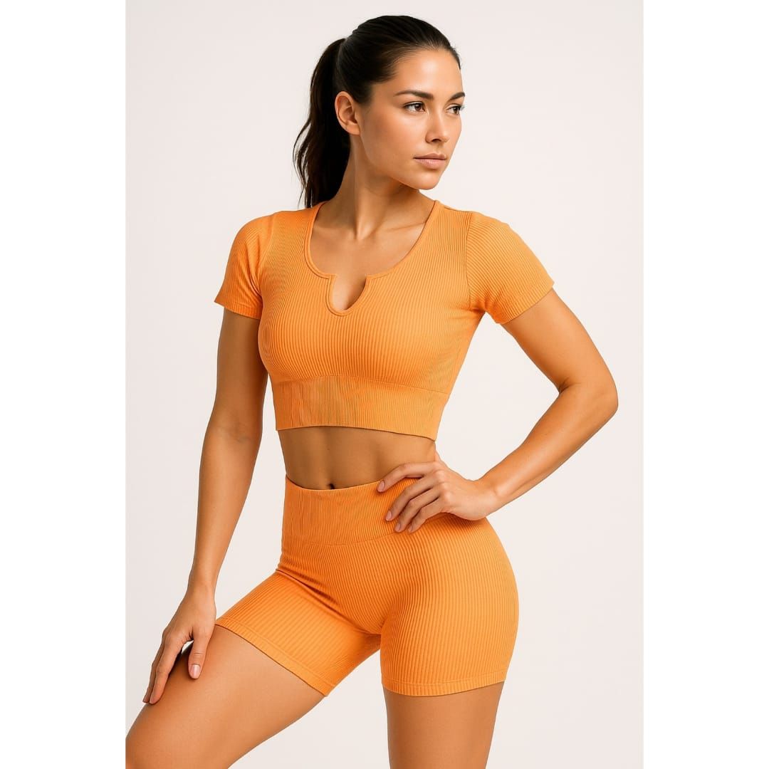 Mujer posando con ropa deportiva naranja sobre un fondo claro liso.
