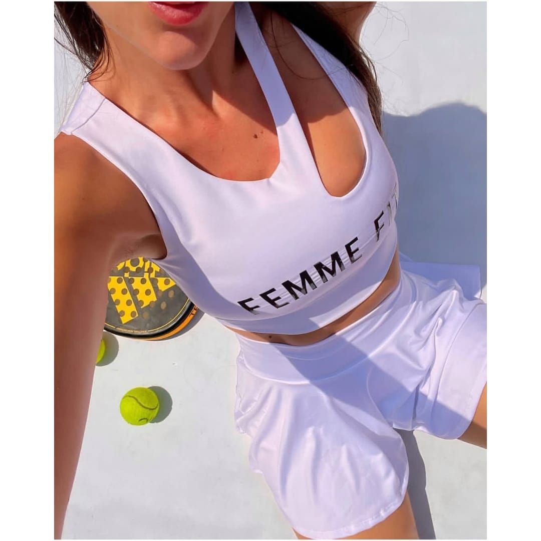 Mujer posando al aire libre con un conjunto deportivo blanco y un top corto con la inscripción 