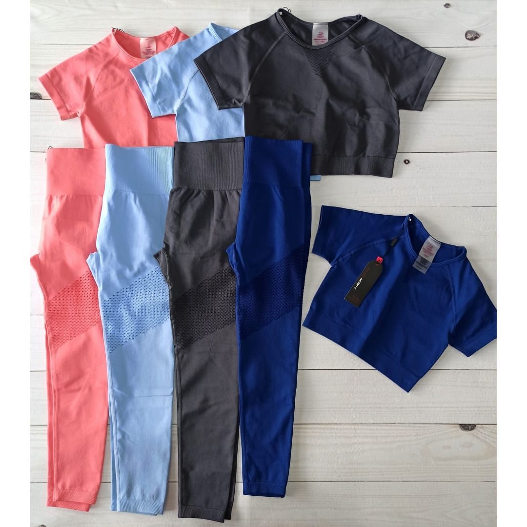 Conjuntos deportivos infantiles en rosa, azul, gris y azul marino extendidos sobre un suelo blanco.