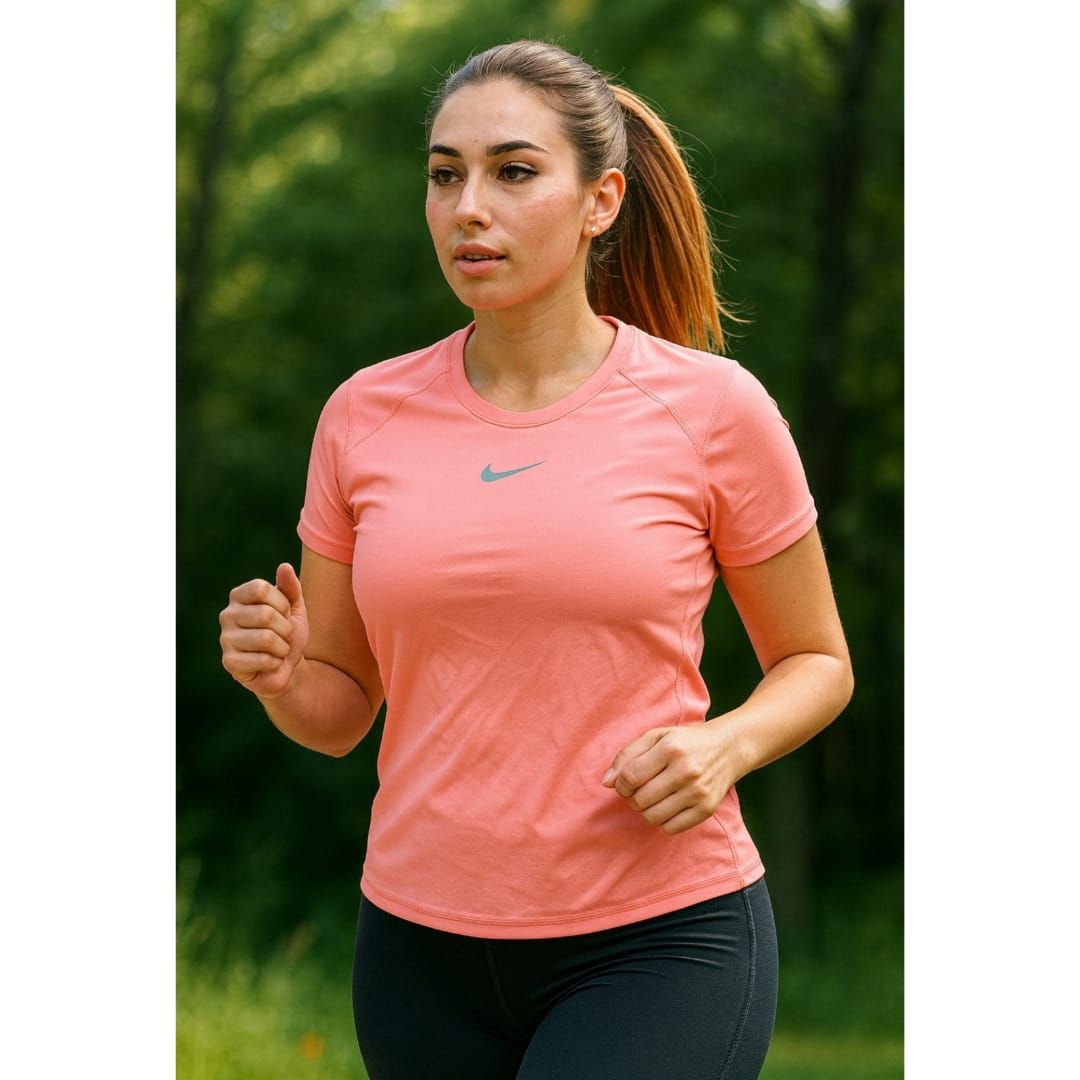 Mujer haciendo ejercicio al aire libre con una camiseta rosa y mallas negras, con vegetación al fondo.