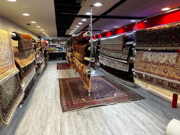 Rug and carpet showroom with colorful Persian-style rugs displayed on both walls and floor