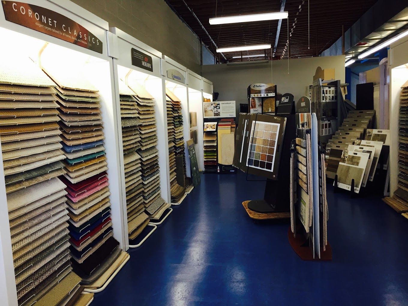 A fabric store aisle with colorful fabric bolts on shelves and racks under bright lights.