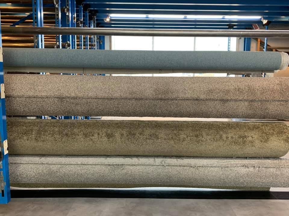 Rows of rolled carpets or mats stacked on shelves in a warehouse