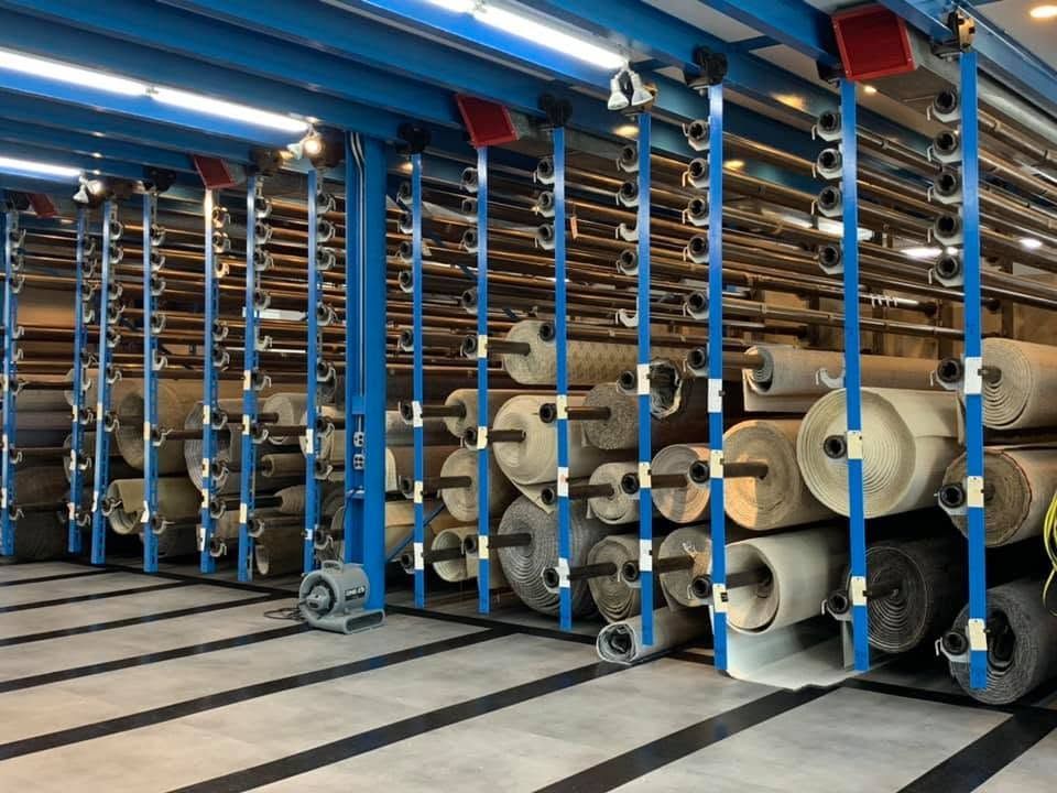 Industrial yarn storage with large spools on blue racks in a warehouse