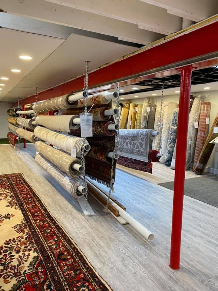 Carpet rolls stacked in a rug store, with patterned rugs displayed along the walls