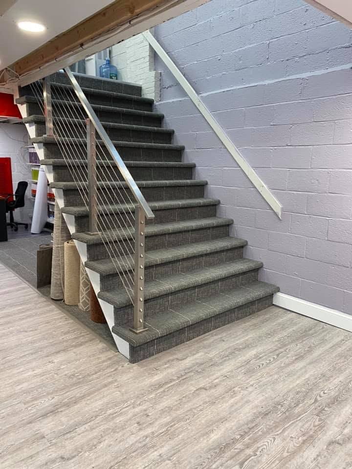 Indoor staircase with gray carpeted steps, metal railing, and lavender wall in a modern office space