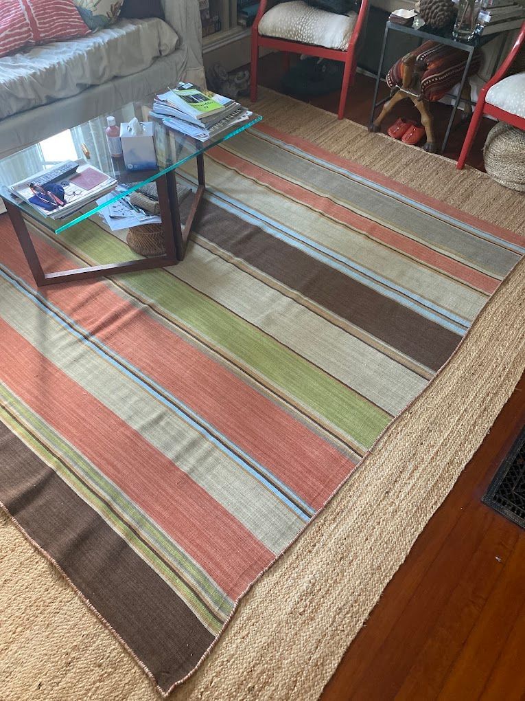 Striped area rug in a living room with a glass coffee table and sofa nearby