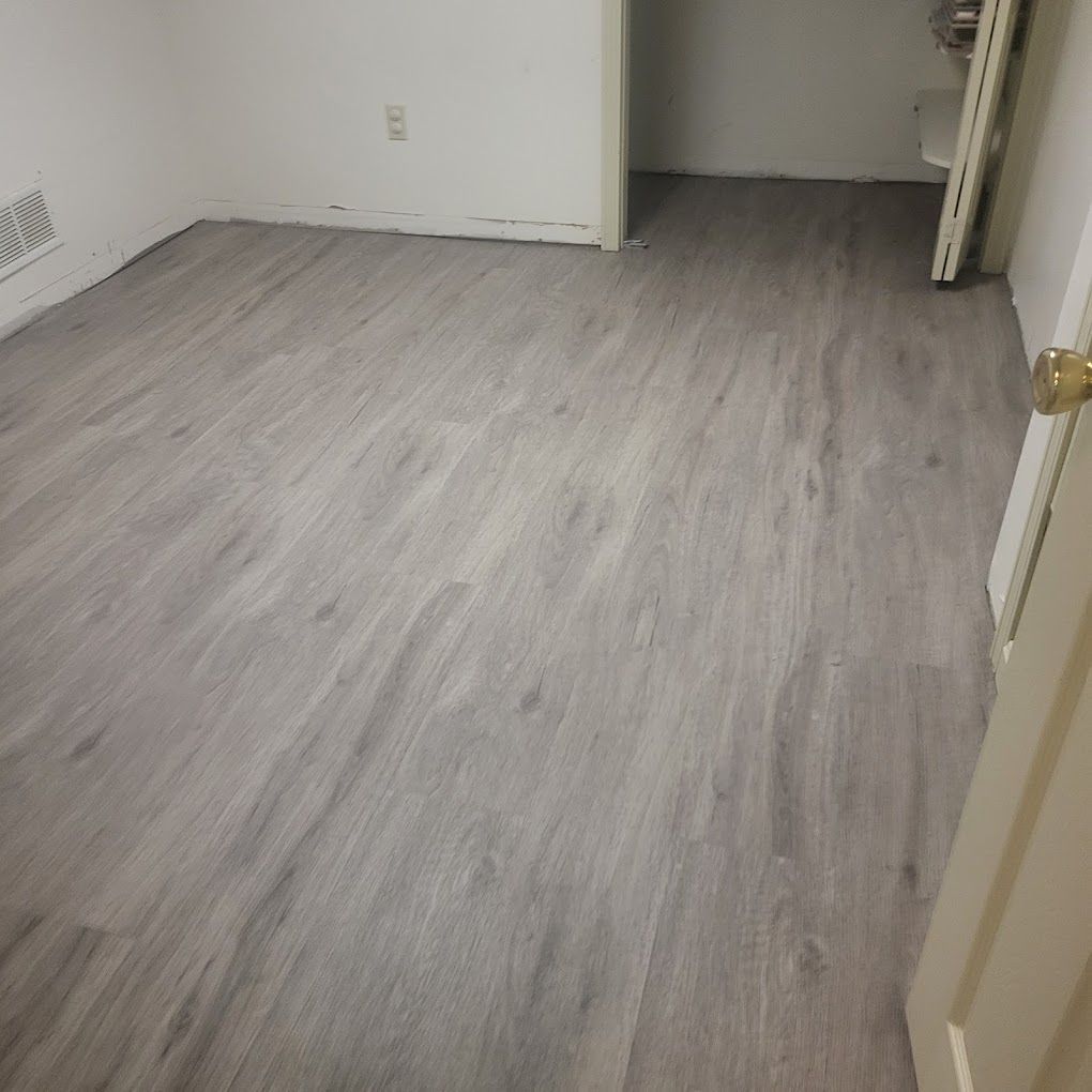 Empty room with light gray wood flooring, white walls, and an open doorway.