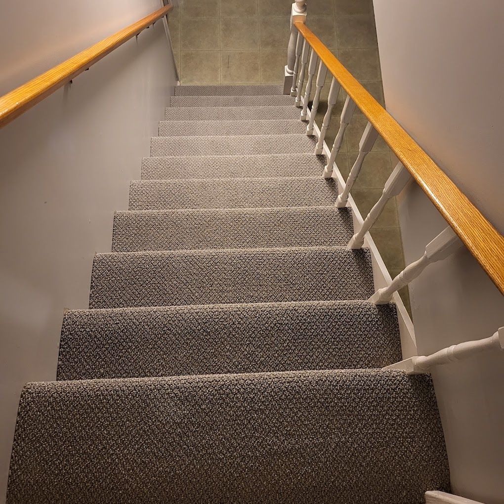 Carpeted indoor staircase with wooden handrails, viewed from the top looking down