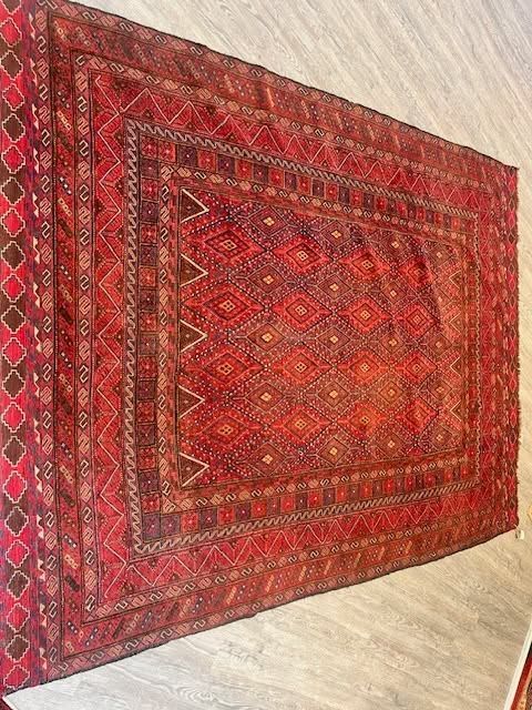Red patterned rectangular rug on a light floor.