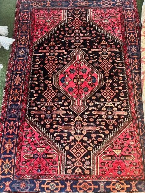 Ornate red, black, and blue patterned Persian rug with a central diamond medallion