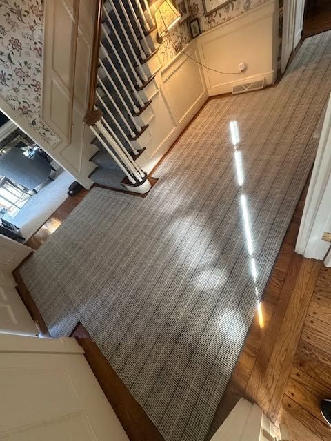 Sunlit carpeted staircase landing with white banister and hardwood floor edge