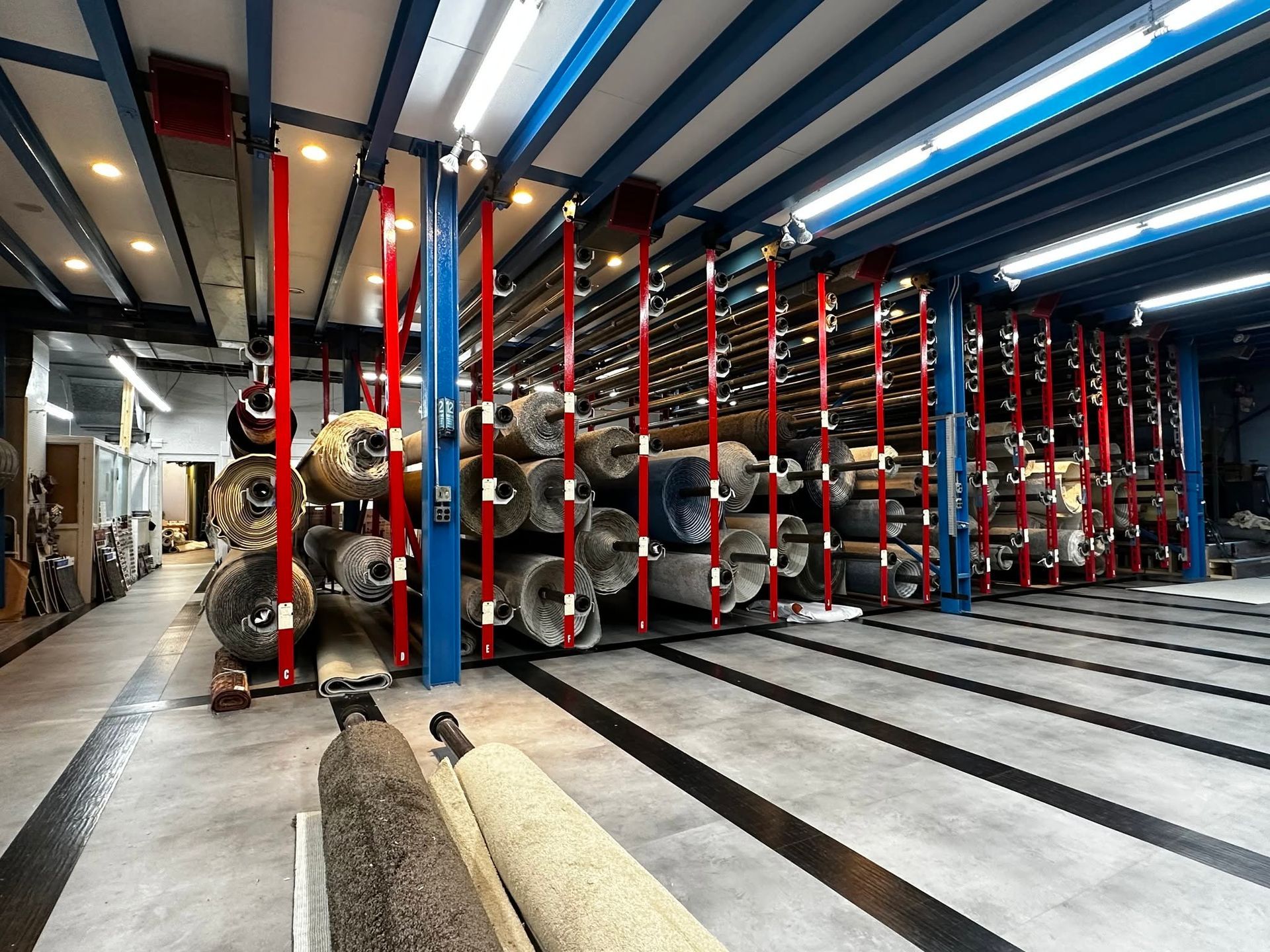 Factory interior with rows of red and blue storage racks under bright ceiling lights