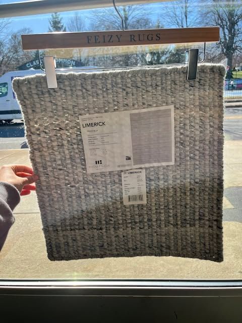Large woven wicker tote with a hanging product tag displayed in a store window.