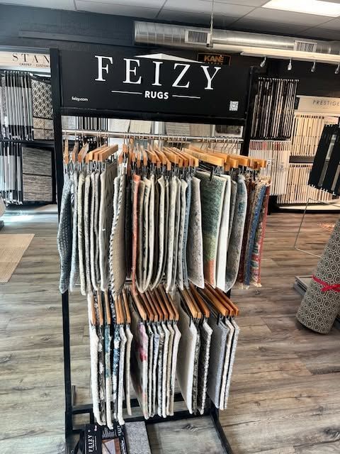 FEIZY rugs display stand with hanging patterned rugs in a store aisle