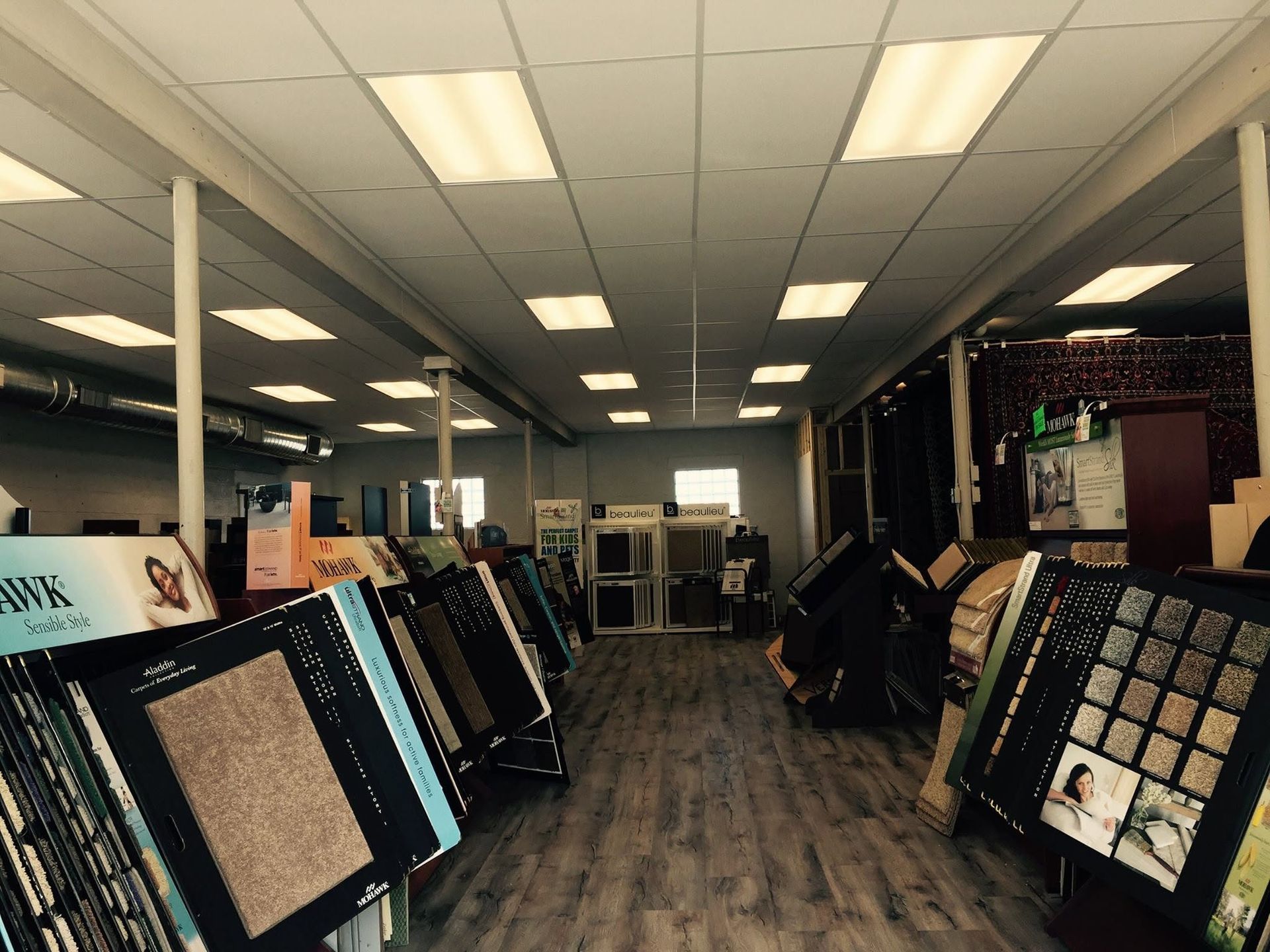 Store interior with rows of framed art displays and ceiling lights along a carpeted aisle