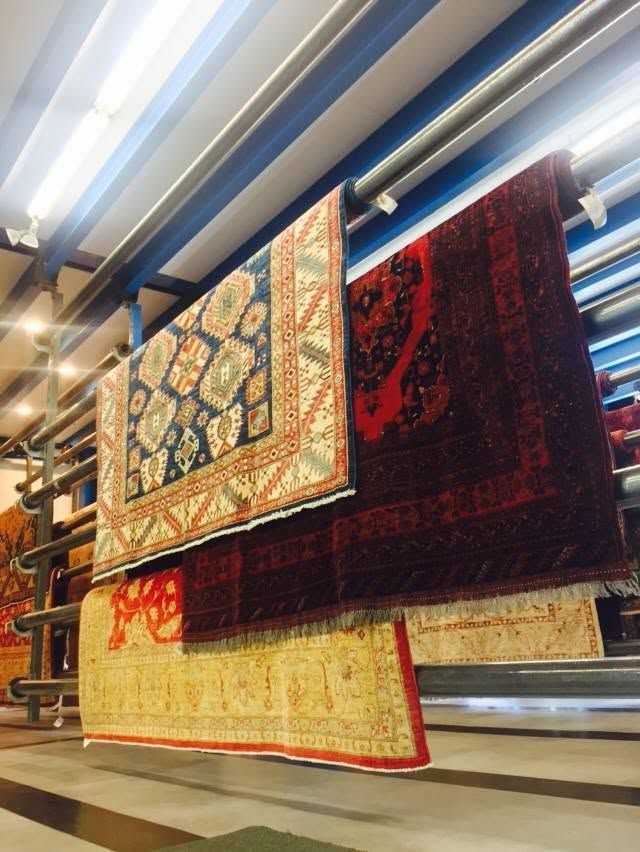 Hanging patterned rugs on display in a brightly lit showroom