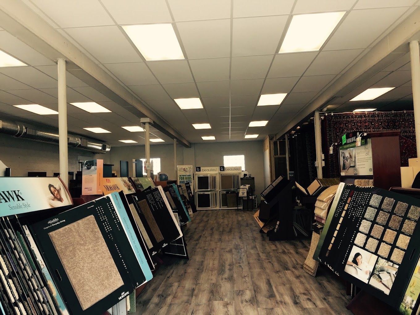 Carpet store showroom with sample flooring displays under bright ceiling lights