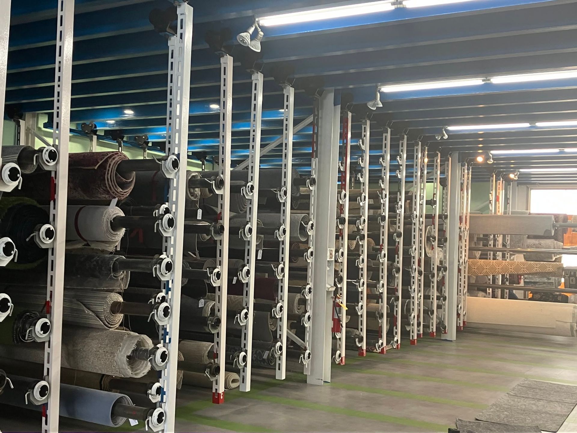 Rows of industrial fabric rolls on storage racks in a large warehouse aisle