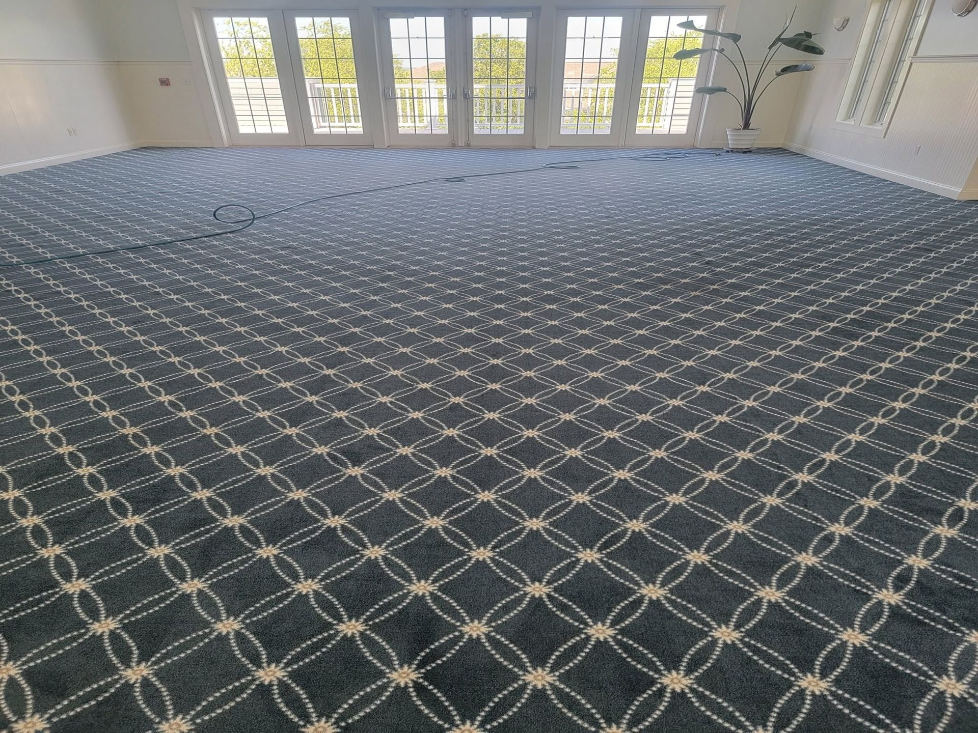 Empty carpeted room with large windows and patterned dark blue carpet floor