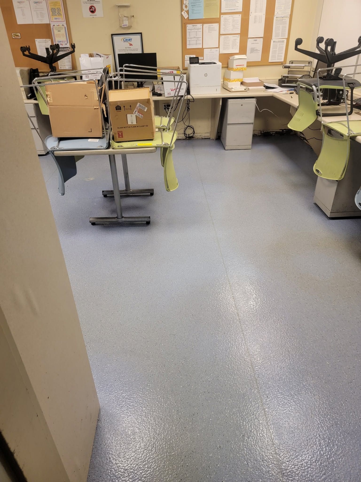 Hospital room with medical equipment, desks, and bulletin boards on a gray floor.