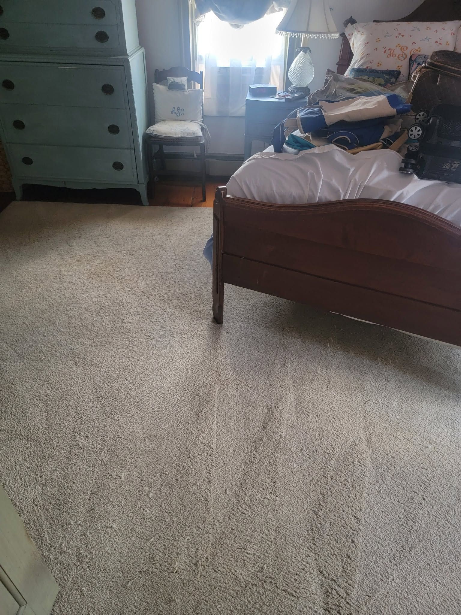 Bedroom with a bed, dresser, and window-lit clutter on the floor and surfaces