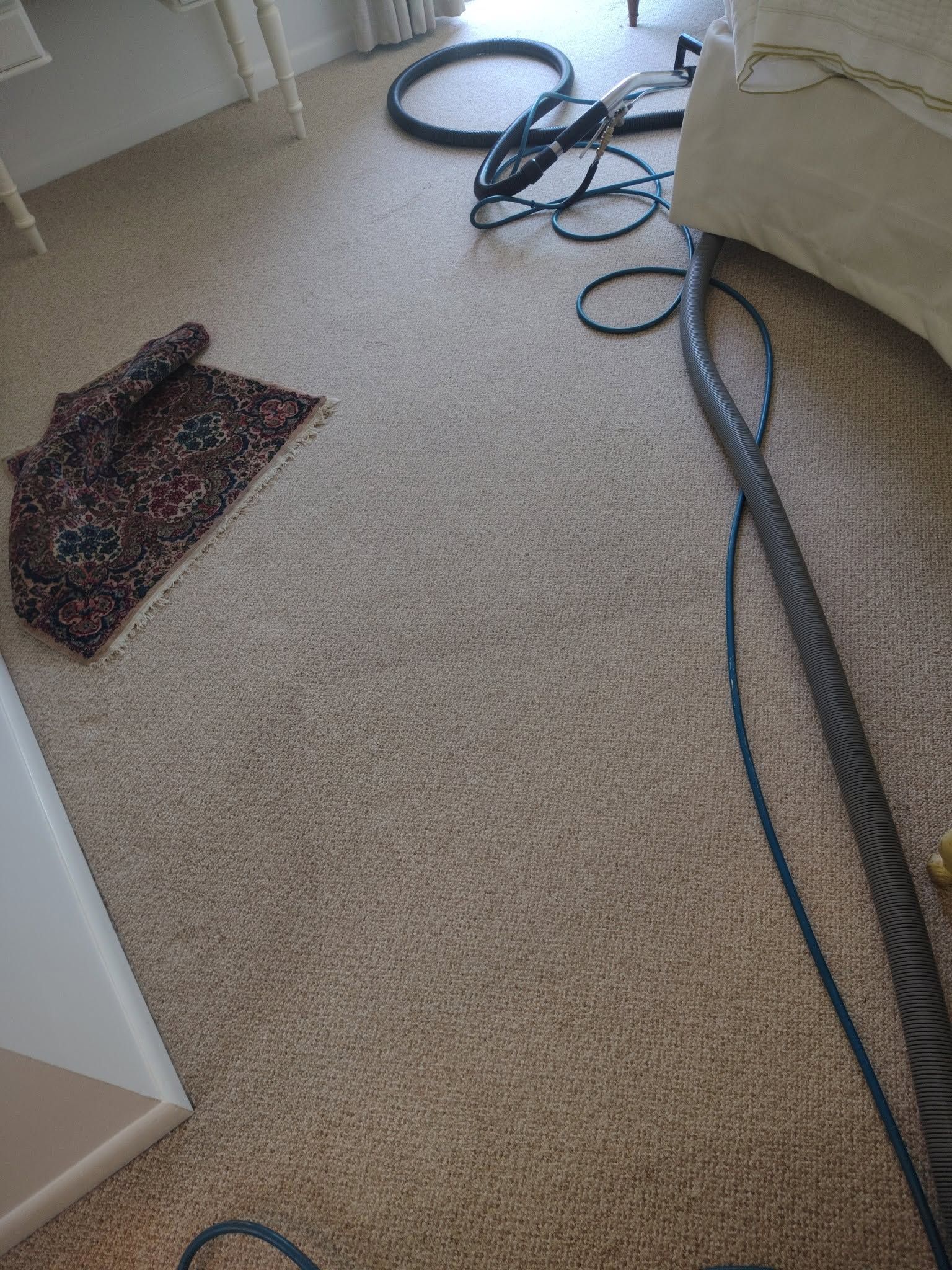 Carpeted room with tangled black cables, a patterned rug, and an open door