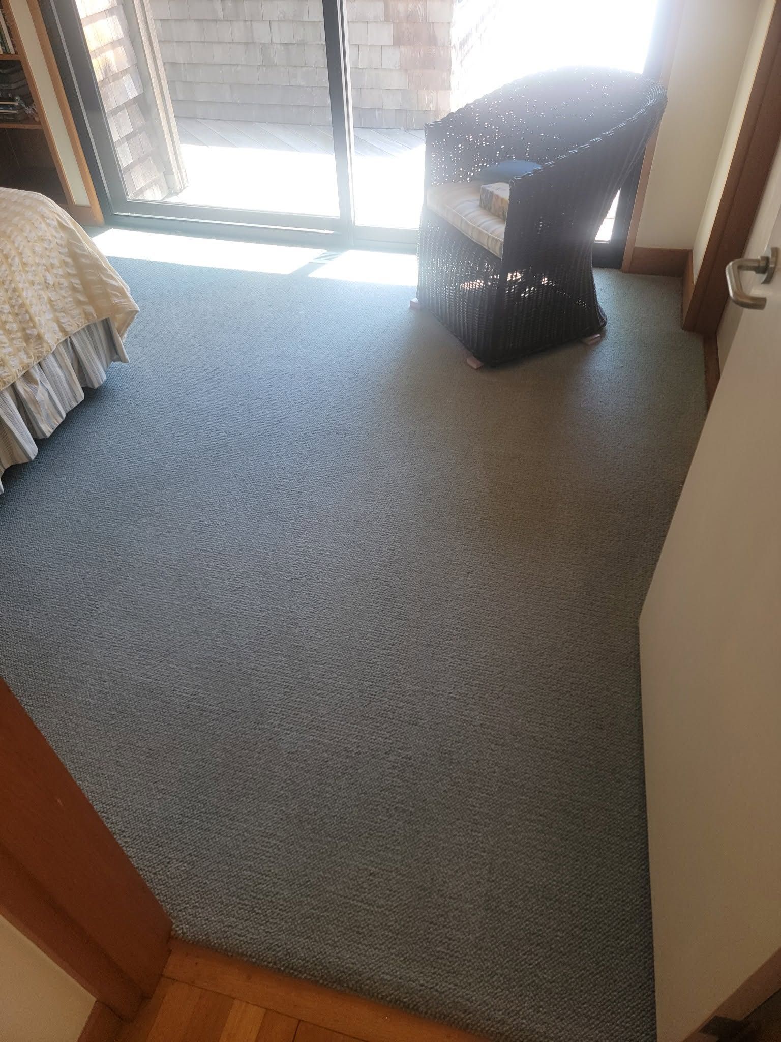 Carpeted room with sliding glass door and a black laundry basket near the window.