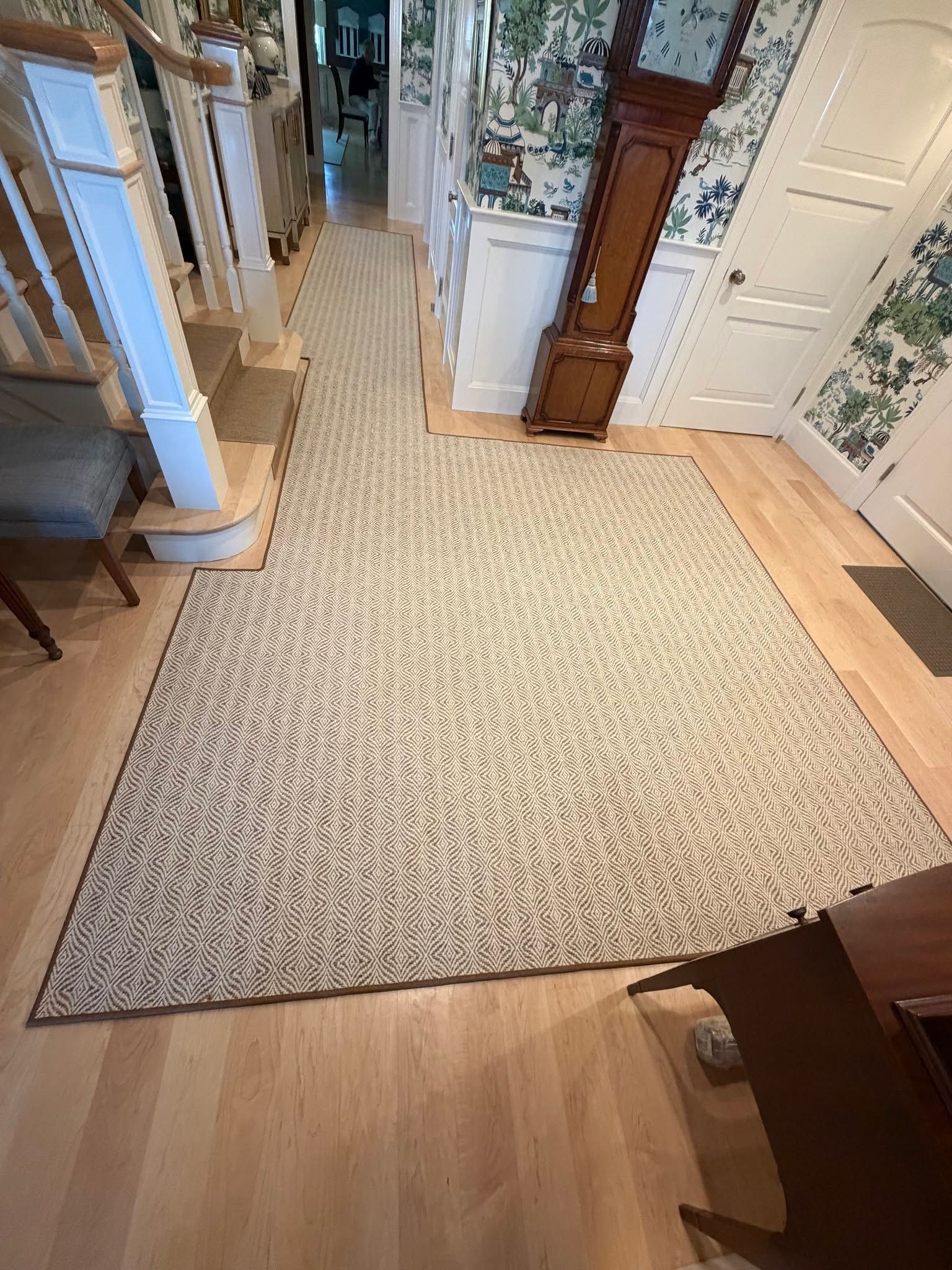 Cream-patterned rug in a bright hallway with wood floors and white doors