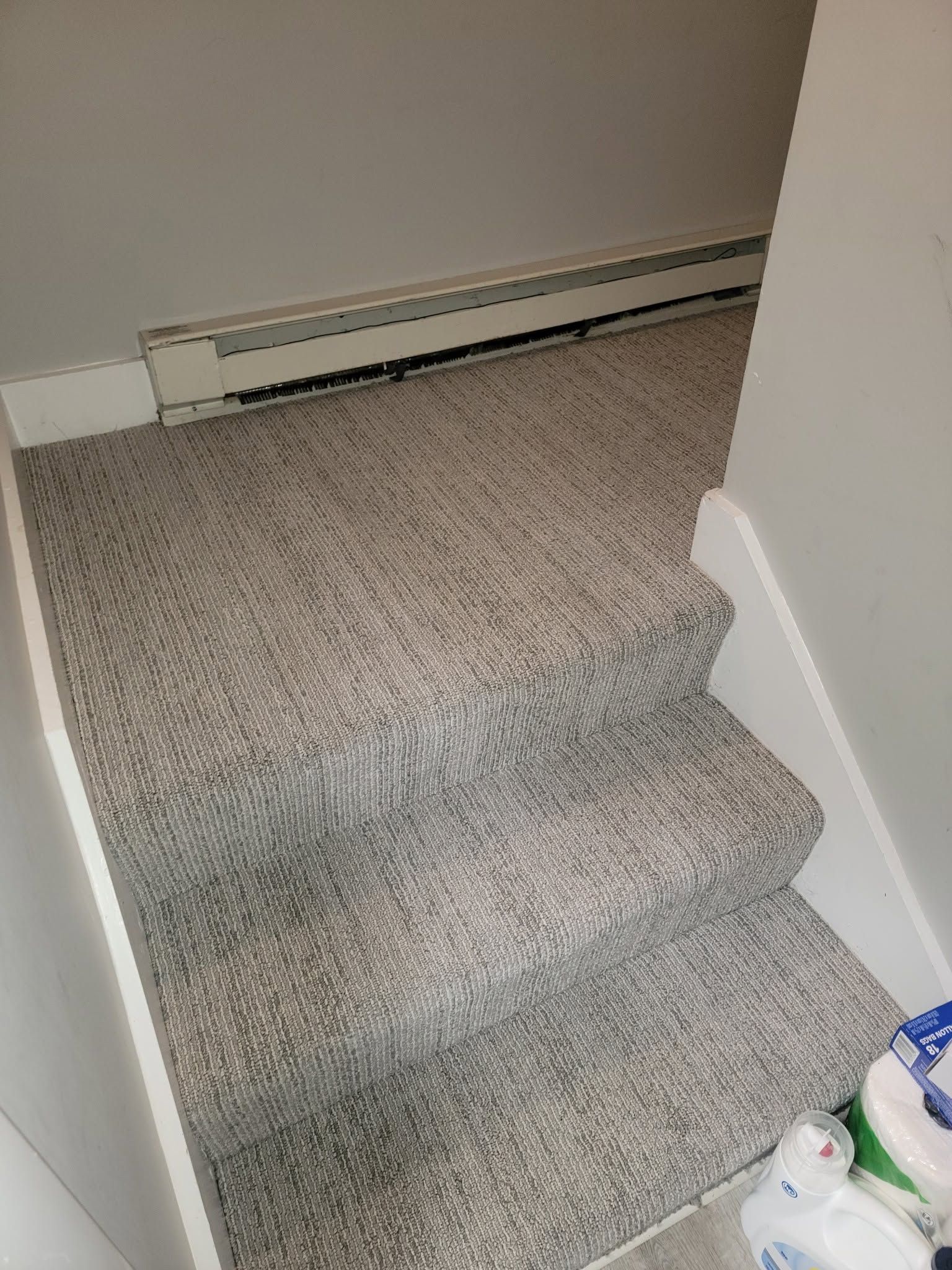 Carpeted staircase with a white baseboard heater along the wall.