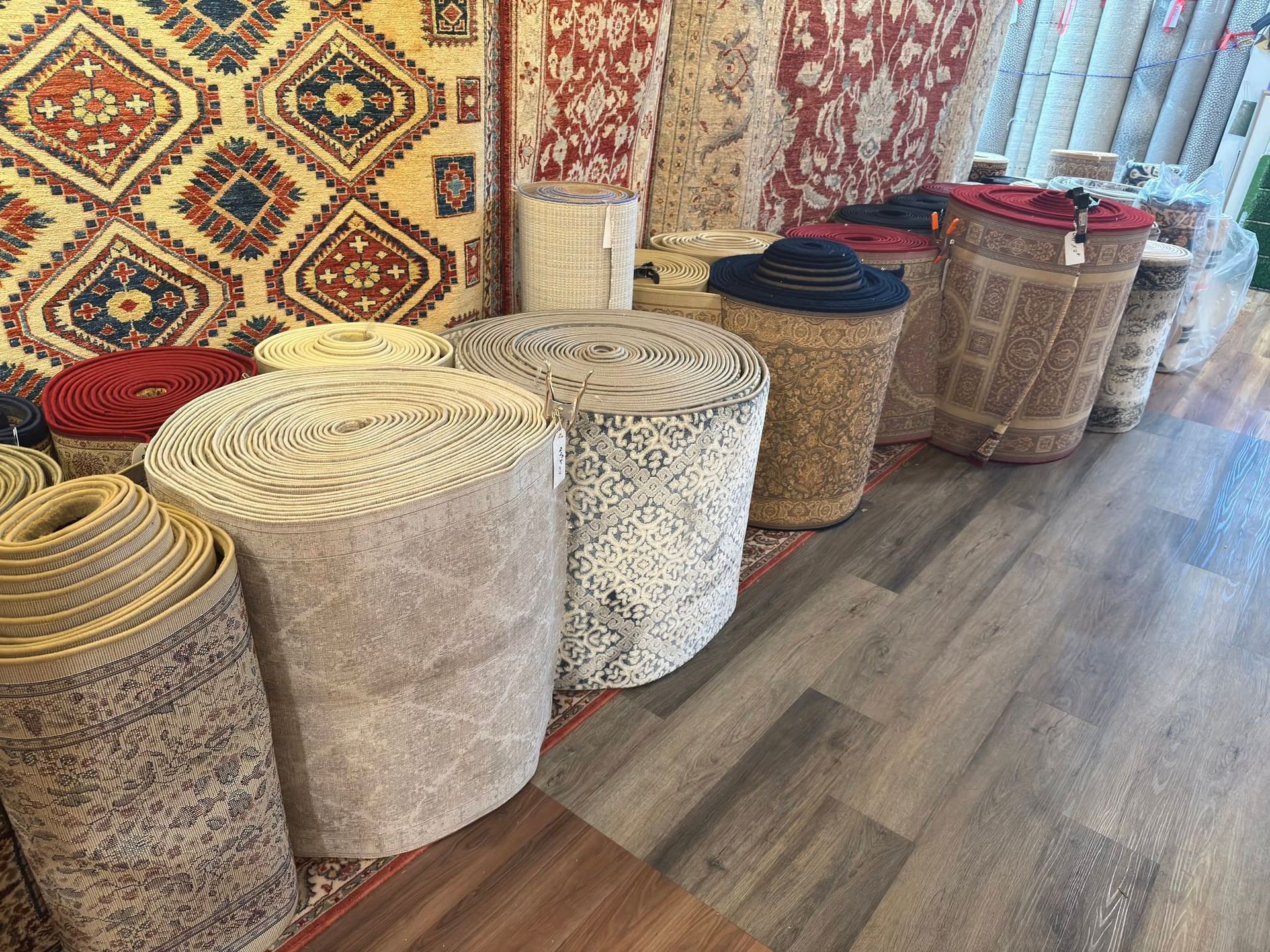 Rolled woven rugs and baskets displayed along a shop wall on a wood floor