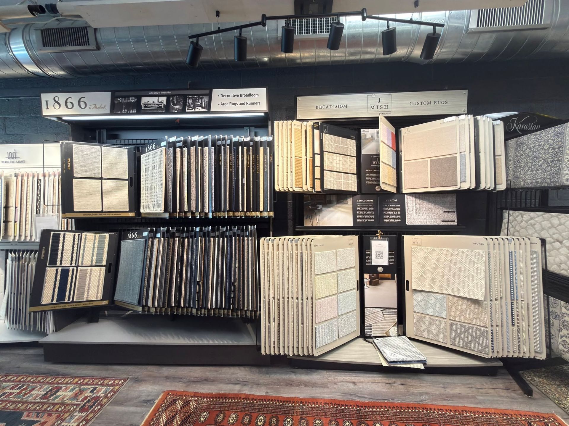 Display of assorted framed samples and art prints arranged on shelves in a store or gallery.