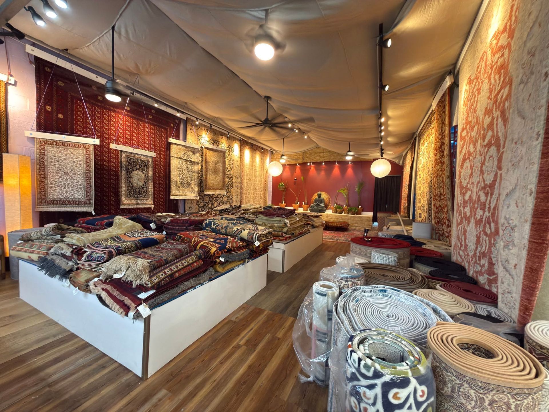 Colorful rugs and textiles displayed in a warmly lit indoor market shop