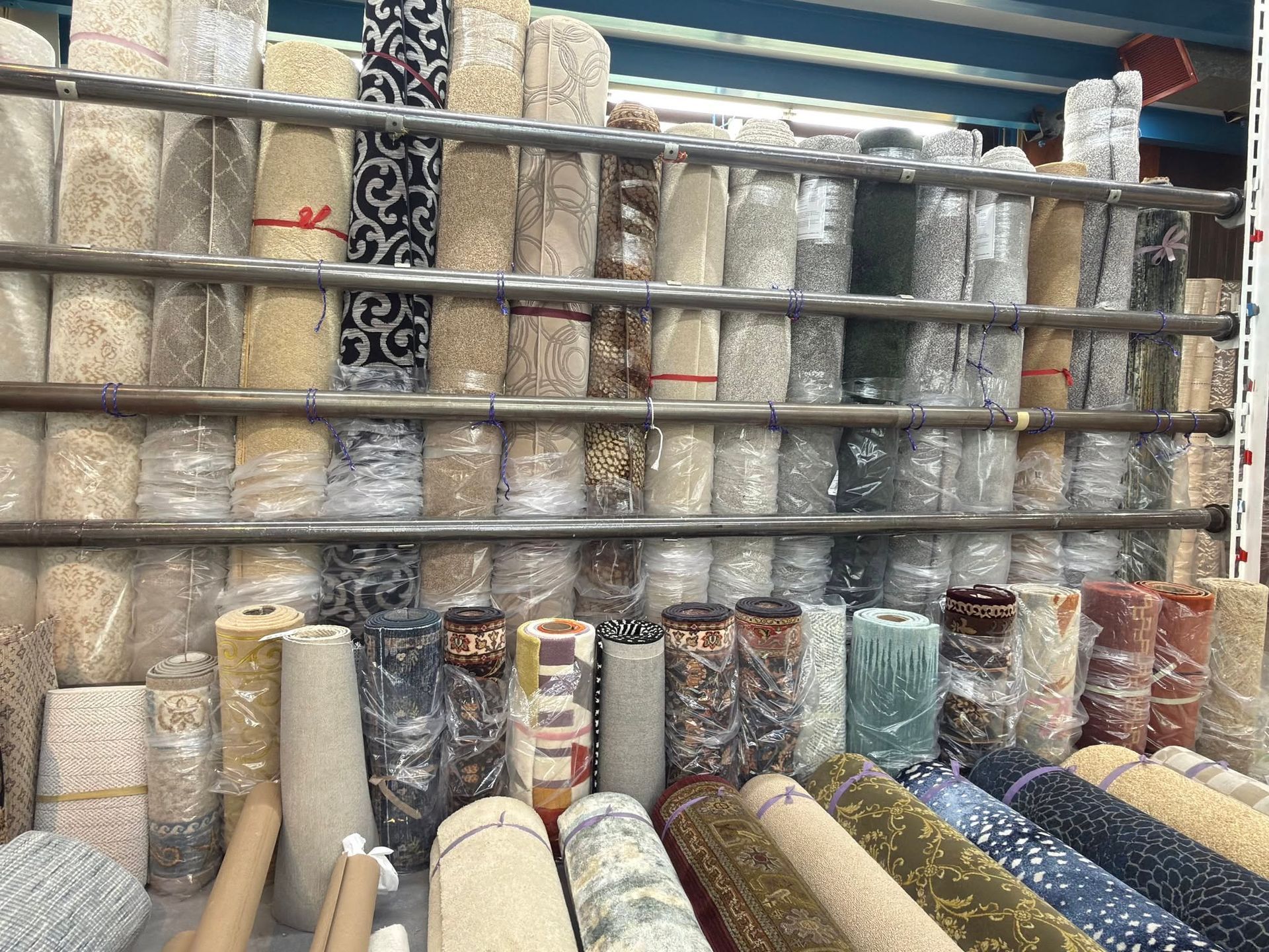 Rolls of patterned wallpaper stacked on store shelves, with samples leaning in the foreground.
